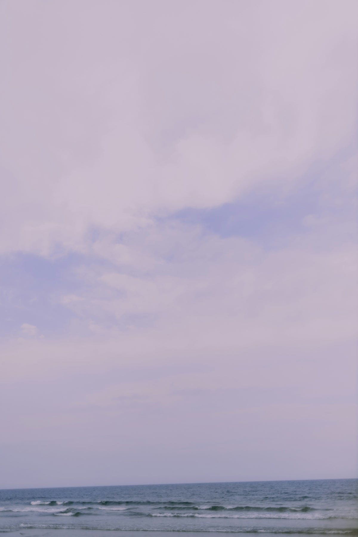 A person standing on a beach holding a surfboard