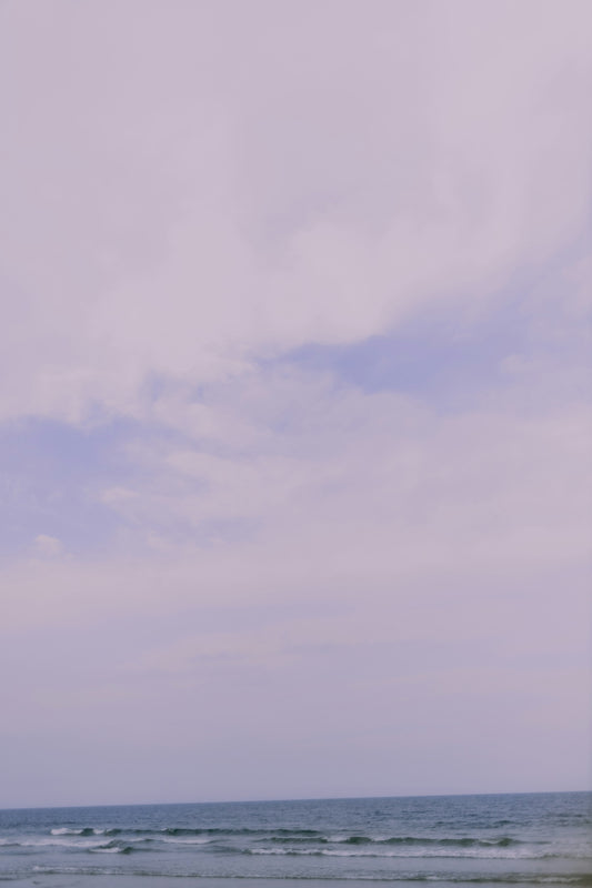 A person standing on a beach holding a surfboard
