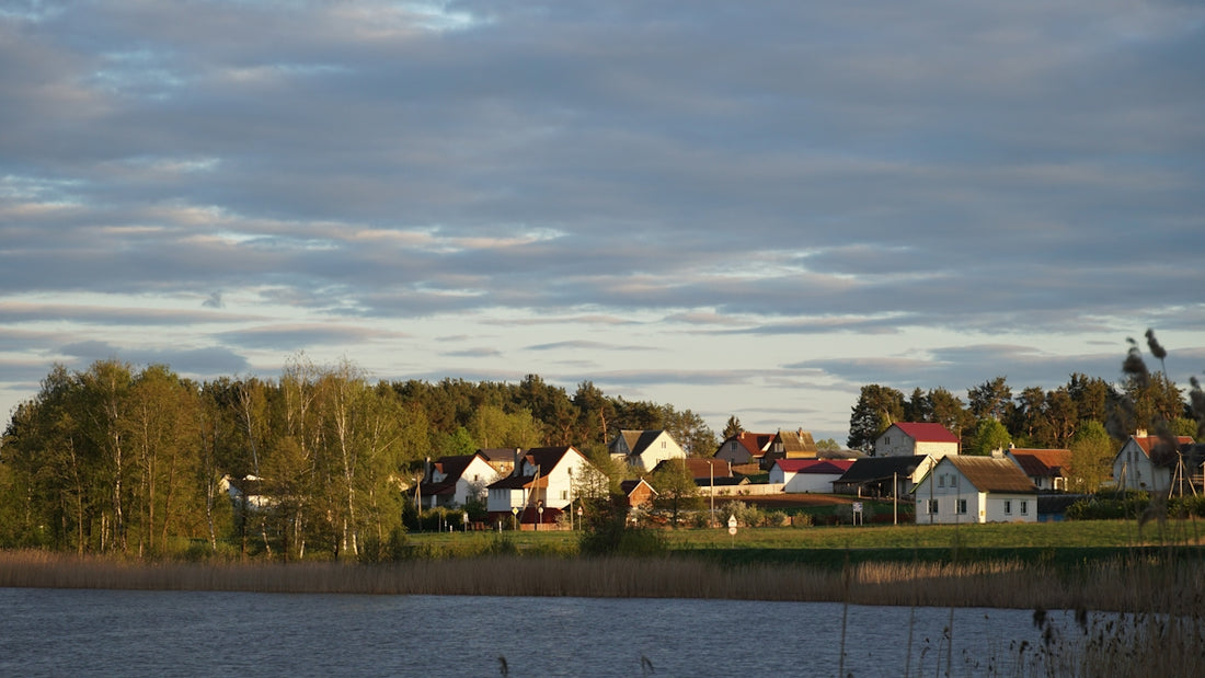 Houses sit near a lake with a cloudy sky.