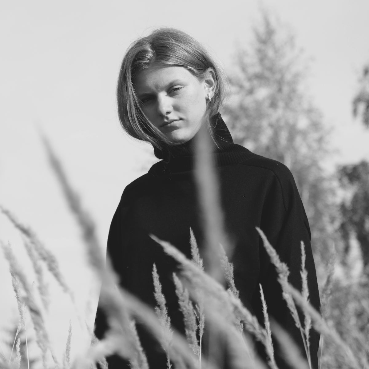 Young woman in black turtleneck standing in tall grass